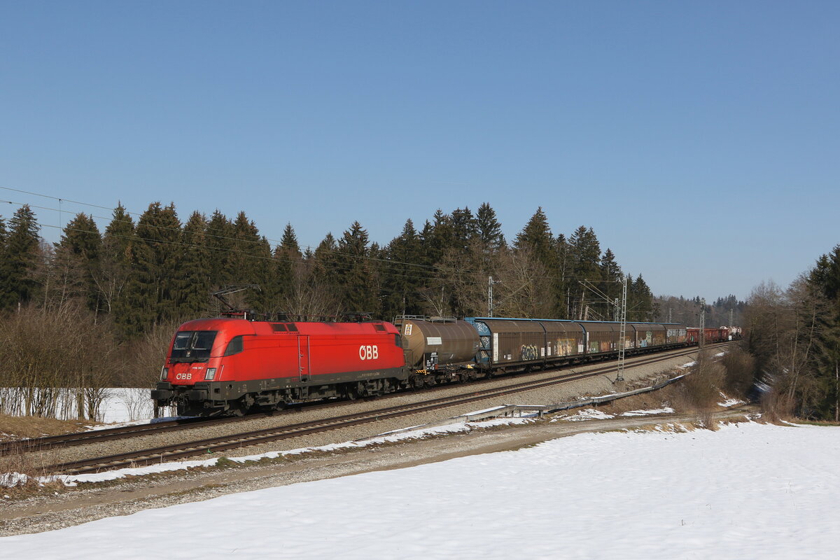 1116 057 war mit einem gemischten G�terzug am 2. M�rz 2023 bei Sossau im Chiemgau in Richtung M�nchen unterwegs.